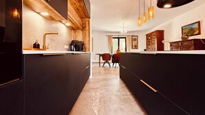 Una cocina moderna con armarios oscuros, una pared de acento de madera e iluminación colgante.