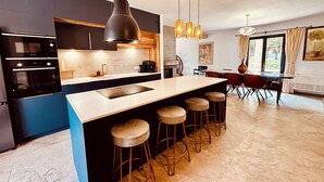Una cocina moderna con una isla central, taburetes de bar e iluminación colgante.
