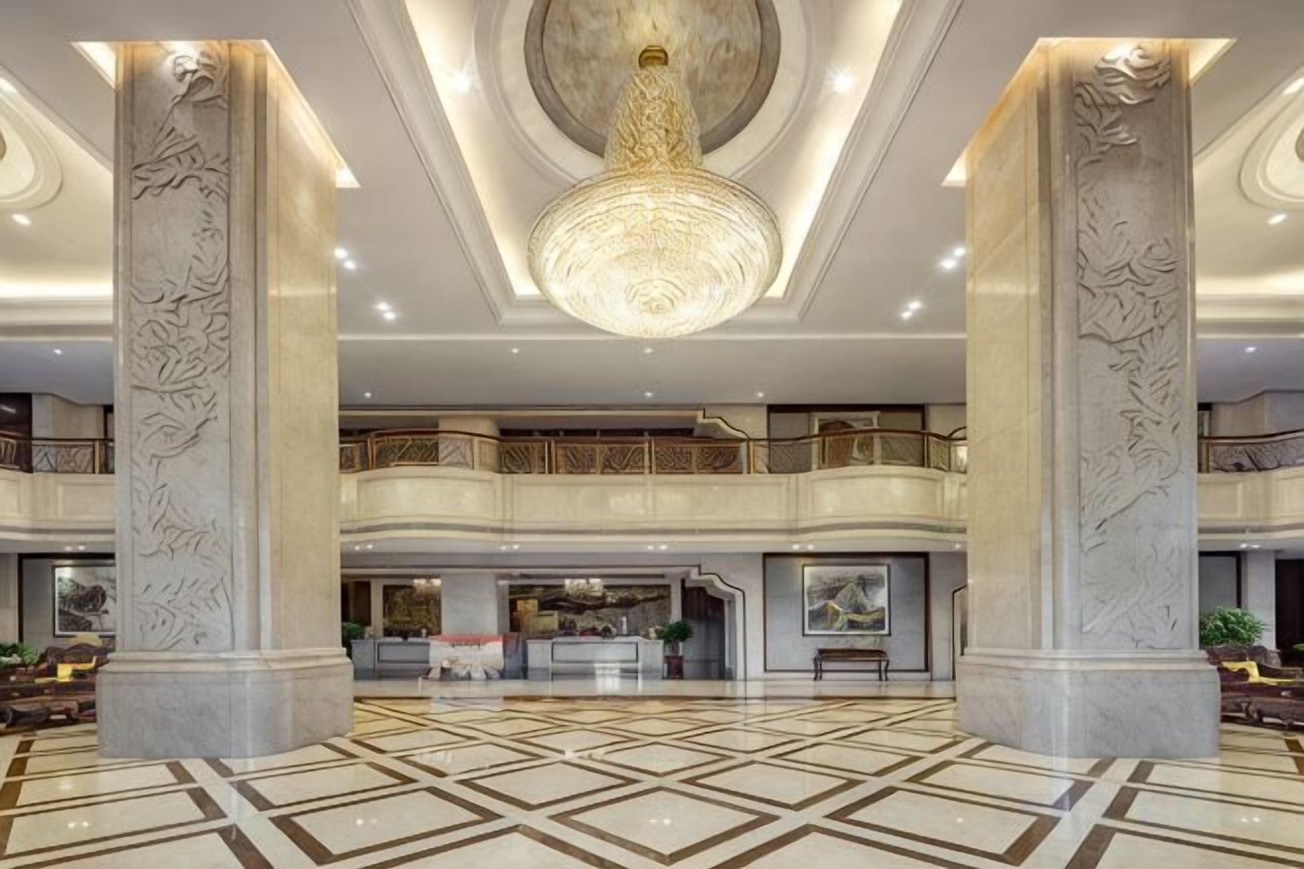 Un hall d’entrée spacieux, doté d’un haut plafond, de colonnes richement décorées et d’un lustre central.
