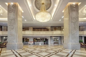A spacious lobby with a high ceiling, ornate columns, and a central chandelier. - Hua He International Hotel (Zhanjiang)