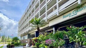 Un hôtel avec une enseigne, des plantes à l’extérieur et un ciel dégagé.