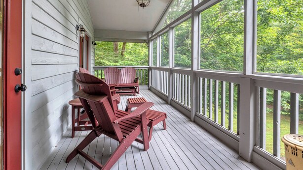 Une véranda couverte avec des chaises en bois et un ventilateur de plafond.