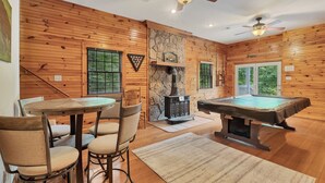 L’intérieur d’un chalet en bois comprend une table de billard, une cheminée et un coin repas.