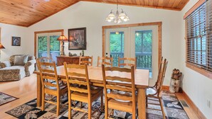 Un coin repas avec une table et des chaises en bois, un ventilateur de plafond et un lustre.