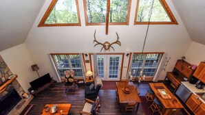 A spacious loft with a high ceiling, large windows, a stone fireplace, and a dining area. - 4 Bedroom 3 Bath on secluded acreage with Fireplace & Wifi (Townsend)