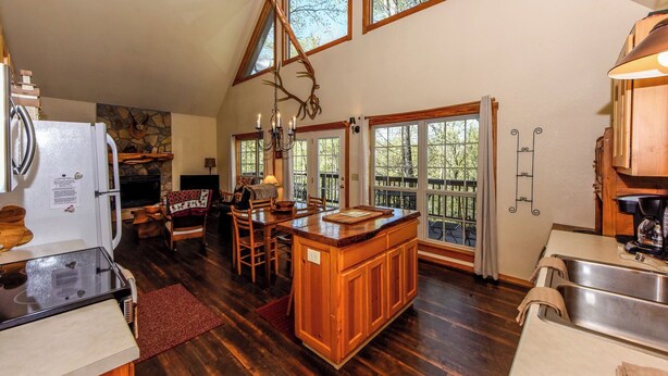 A spacious kitchen with wooden cabinets, a large island, and a dining area with a fireplace. - 4 Bedroom 3 Bath on secluded acreage with Fireplace & Wifi (Townsend)