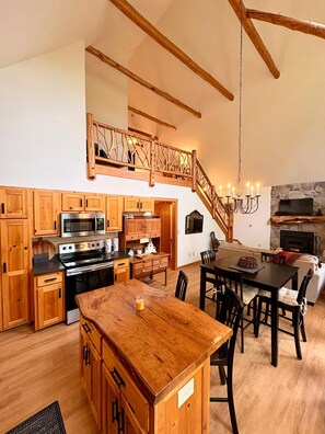 Una cocina amplia con armarios de madera, una isla central y una chimenea de piedra.