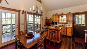 A spacious kitchen with wooden cabinets, a central island with stools, and a chandelier. - 4 Bedroom 3 Bath on secluded acreage with Fireplace & Wifi (Townsend)