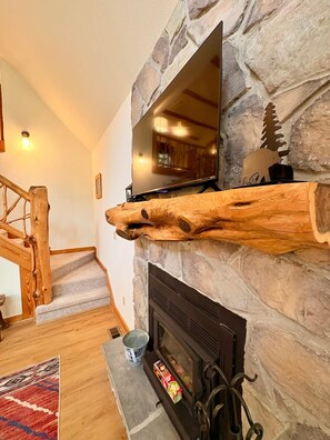 Una chimenea de piedra con un televisor montado encima.