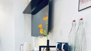 Un comedor moderno con una mesa de madera, sillas y un florero con flores.