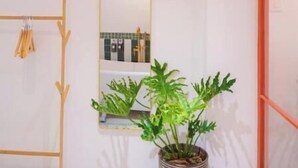 A bathroom with a wooden rack, a large mirror, and a potted plant. - ZY 4. Little Saigon Balcony -- Riverside Vibrant D1 (Ho Chi Minh)