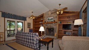 A cozy living room with a fireplace, a sofa, a television, and a ceiling fan. - Cabin with wonderful mountain views, 2 BR/2 BA, sleeps 6 (Townsend)