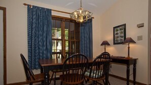 A dining area with a wooden table and chairs, a chandelier, and a window with curtains. - Cabin with wonderful mountain views, 2 BR/2 BA, sleeps 6 (Townsend)