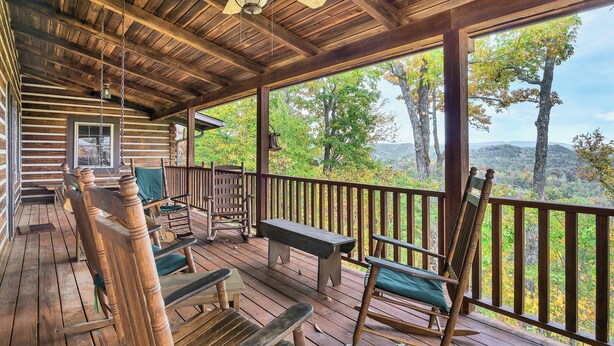 A wooden deck with rocking chairs and a bench, overlooking a forested landscape. - TRANQUILITY 4 BR 4 1/2 Bath Log Cabin with Acreage and Views for Miles (Townsend)