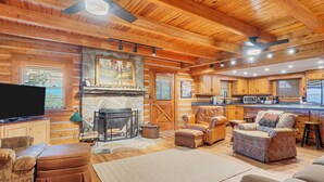 A log cabin interior with a fireplace, wooden furniture, and a kitchen area. - TRANQUILITY 4 BR 4 1/2 Bath Log Cabin with Acreage and Views for Miles (Townsend)