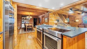 A modern kitchen with wooden walls, stainless steel appliances, and a central island. - TRANQUILITY 4 BR 4 1/2 Bath Log Cabin with Acreage and Views for Miles (Townsend)