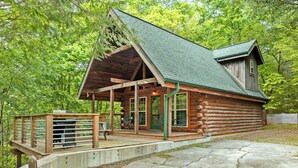 A log cabin with a porch, a covered deck, and a concrete driveway. - Authentic log cabin with the real feel of serenity in a Golf Course Vicinity. (Townsend)