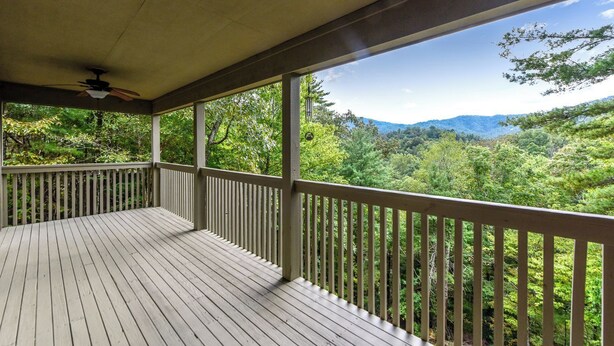 A wooden deck with a railing overlooking a forested landscape. - This cozy home is located on a situated on a mountainside is welcoming! (Townsend)