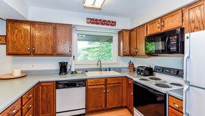 A modern kitchen with wooden cabinets, a built-in microwave, a stove, and a dishwasher. - This cozy home is located on a situated on a mountainside is welcoming! (Townsend)