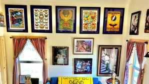 Un soggiorno con un divano blu, poster incorniciati alle pareti, un tavolino da caffè con libri e un tappeto decorato.