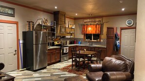 Una cucina compatta con elettrodomestici moderni, una zona pranzo con mobili in pelle e un accogliente soggiorno con tappeto decorato.