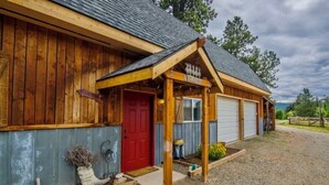 Un edificio in legno con una porta rossa, un garage e un portico coperto.