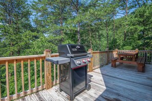 Un barbecue installé sur une terrasse en bois, avec vue sur une forêt.