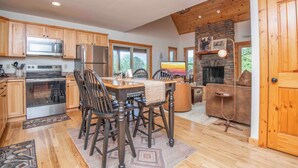 Une cuisine spacieuse avec des meubles en bois, un grand îlot central et une cheminée en pierre.