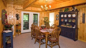 Une salle à manger en bois, avec une table et des chaises, un lustre et un porte-assiettes fixé au mur.