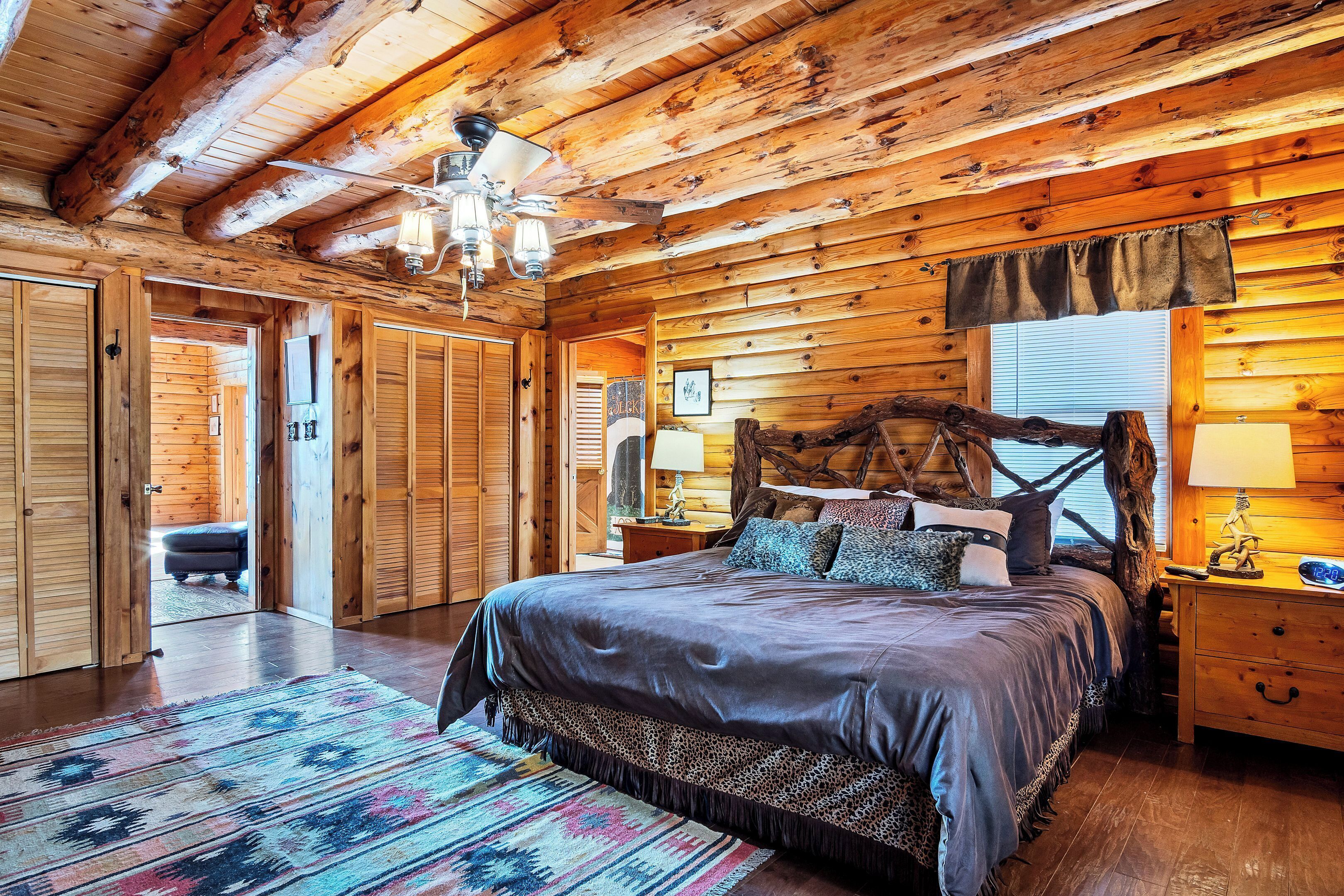 A log cabin bedroom with a large bed, wooden walls, and a chandelier.