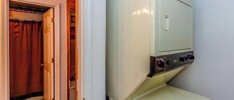 A compact laundry room with a washing machine and dryer, a door with a towel rack, and a patterned floor.