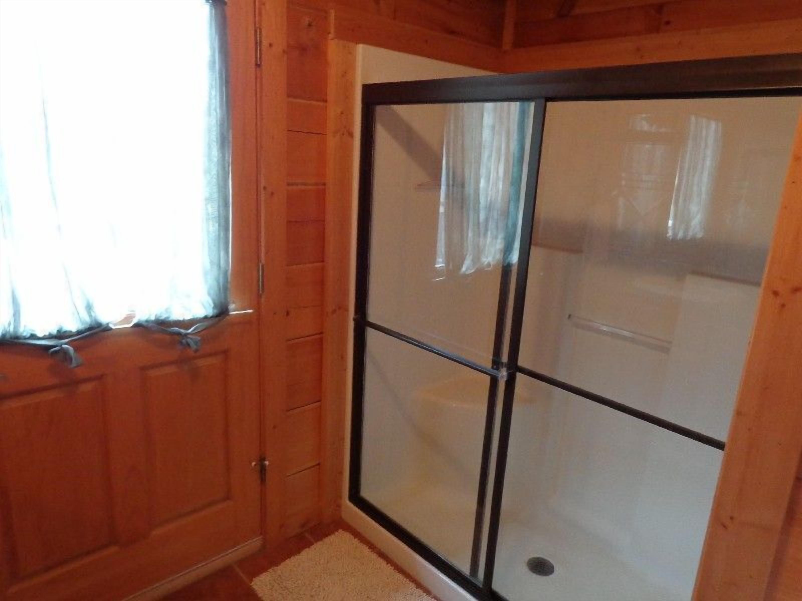 Una habitación de madera con un ventanal corredero que da a una zona de ducha.