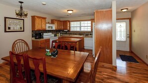 A spacious kitchen with wooden cabinets, a dining table, and a chandelier.