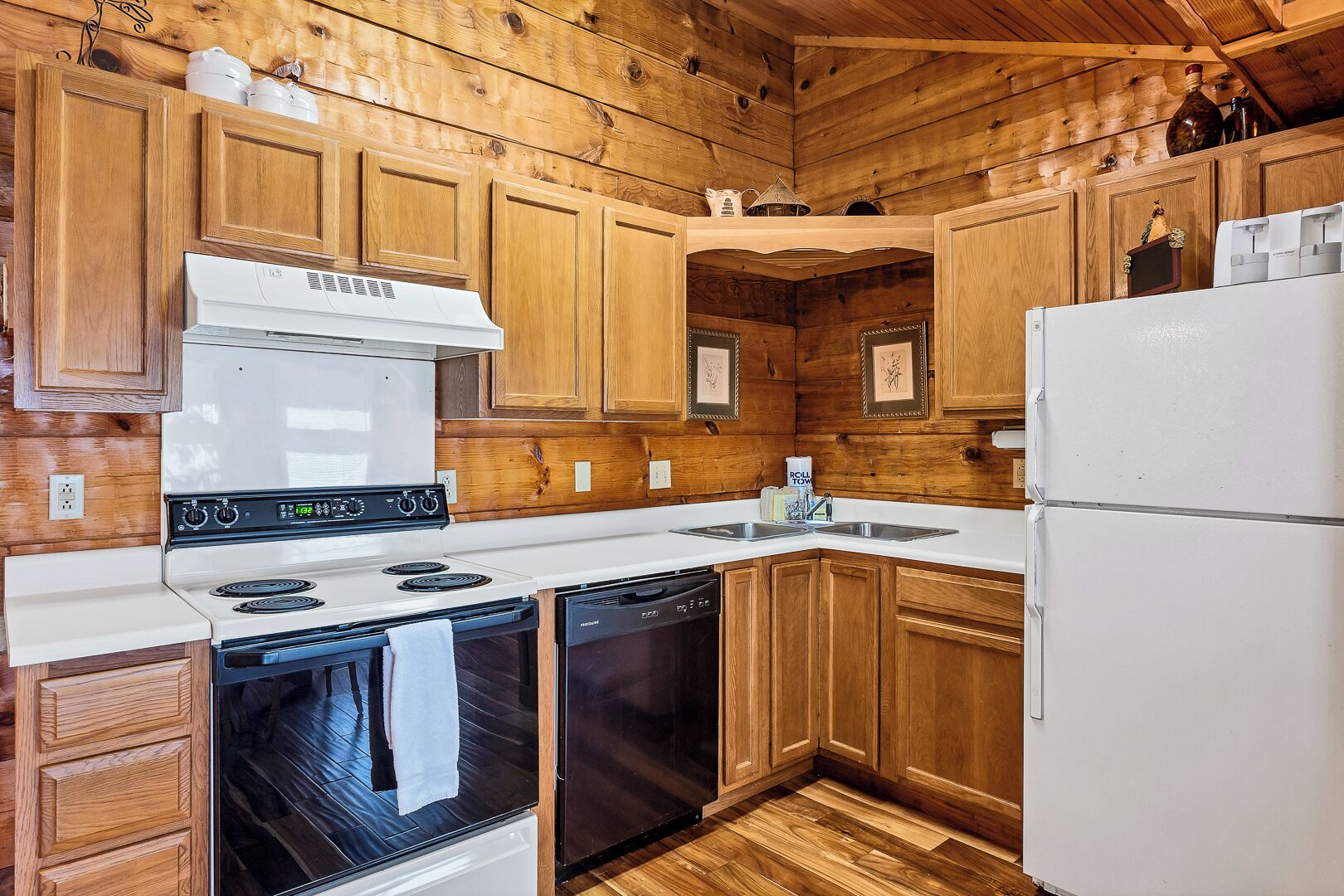 A kitchen with wooden cabinets, a white stove, a dishwasher, and a refrigerator.