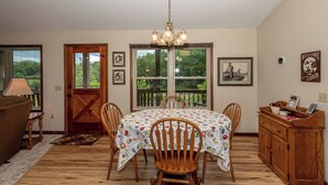 A dining area with a wooden table, chairs, and a chandelier. There is a wooden cabinet with a 'Welcome to the Cabin' sign. - This home is located on a beautiful golf course community and has a view (Townsend)