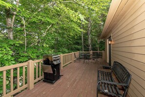 A wooden deck with a grill, outdoor furniture, and a bench. - This home is located on a beautiful golf course community and has a view (Townsend)