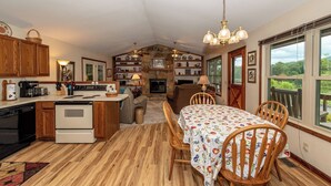 A cozy kitchen with wooden cabinets, a dining table with chairs, and a stone fireplace. - This home is located on a beautiful golf course community and has a view (Townsend)