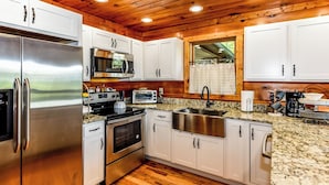 A modern kitchen with stainless steel appliances, granite countertops, and white cabinetry.