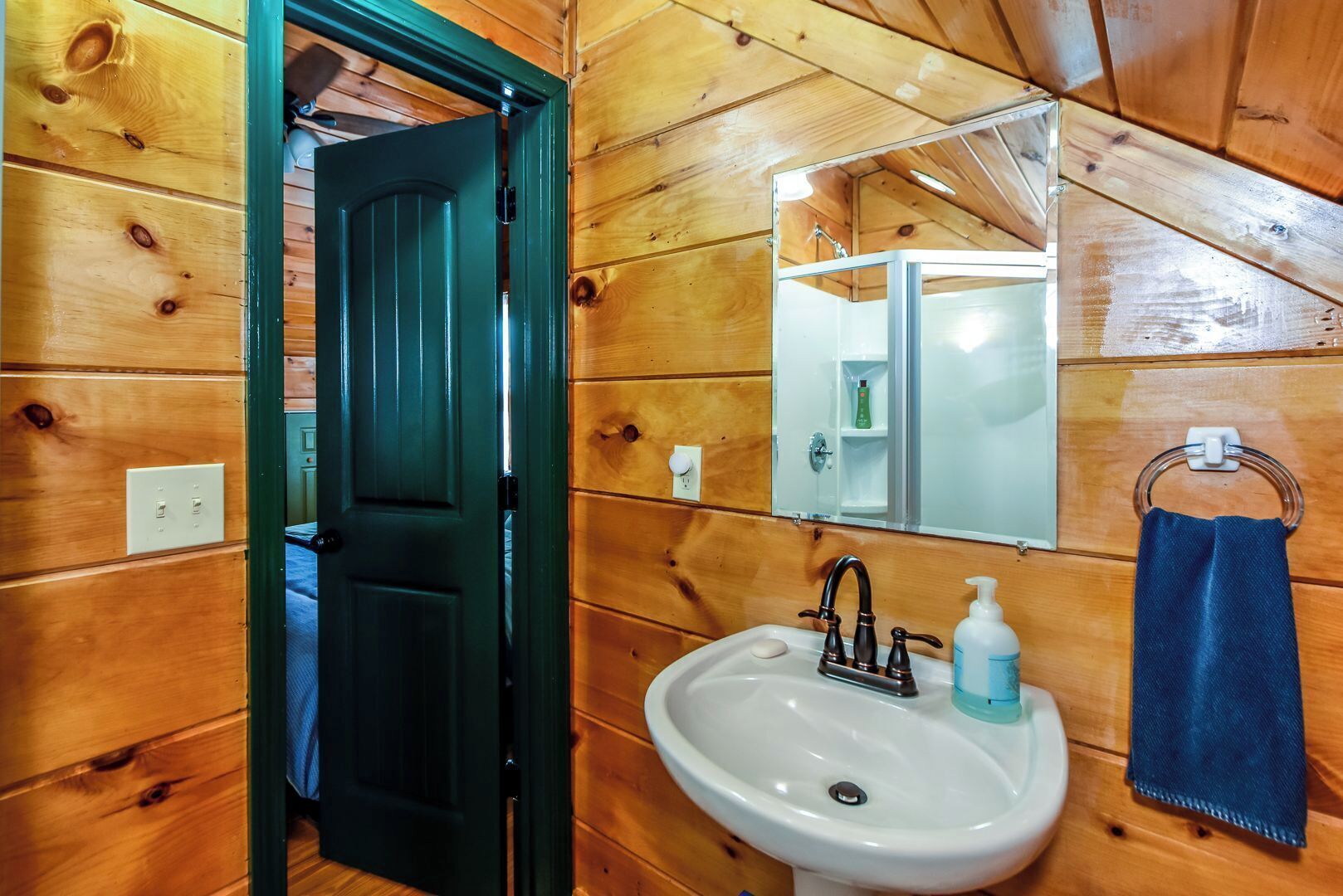 A wooden-paneled bathroom with a white sink, a mirror, and a towel rack.
