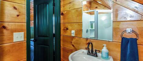 A wooden-paneled bathroom with a white sink, a mirror, and a towel rack.