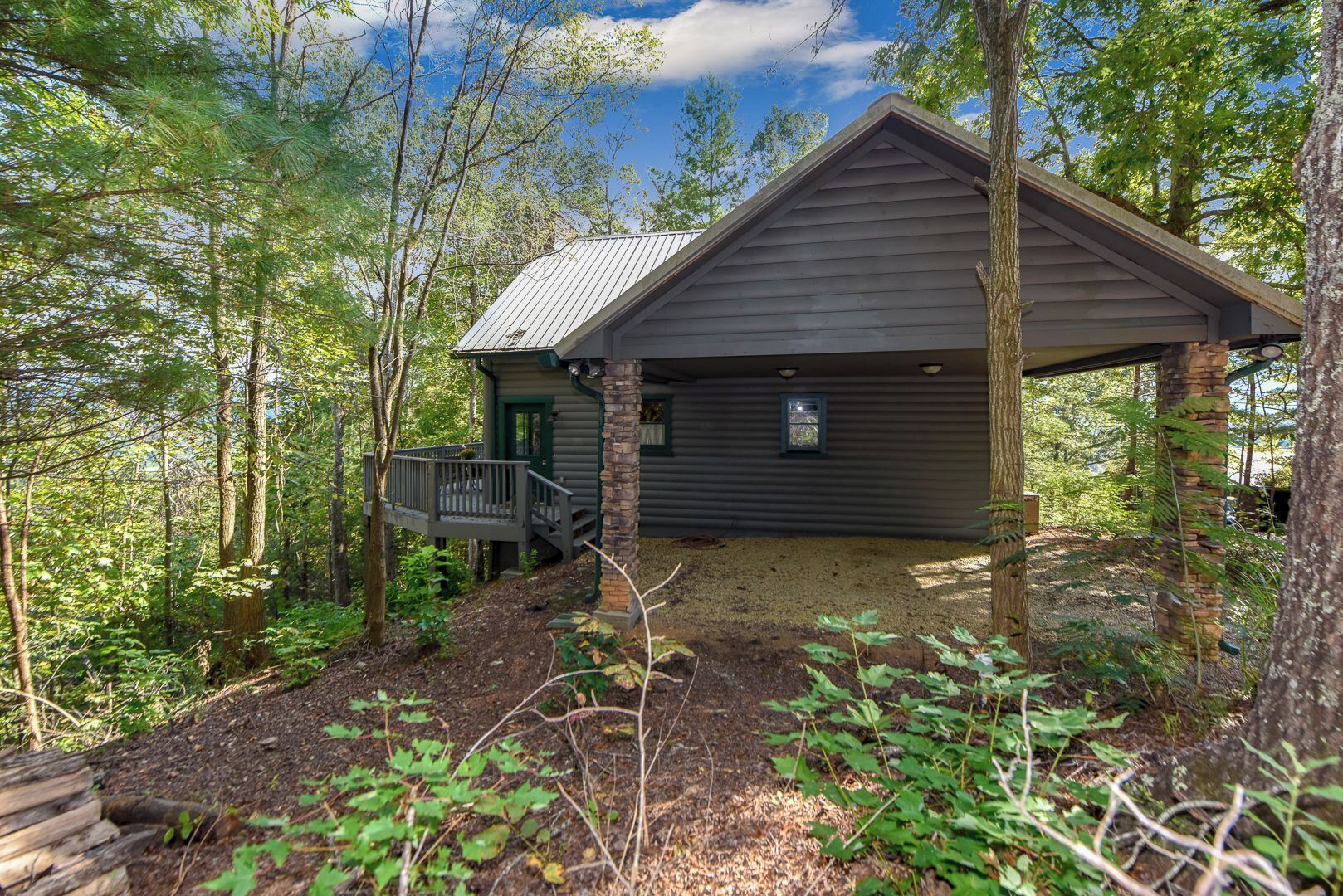 A cabin with a porch, surrounded by trees.