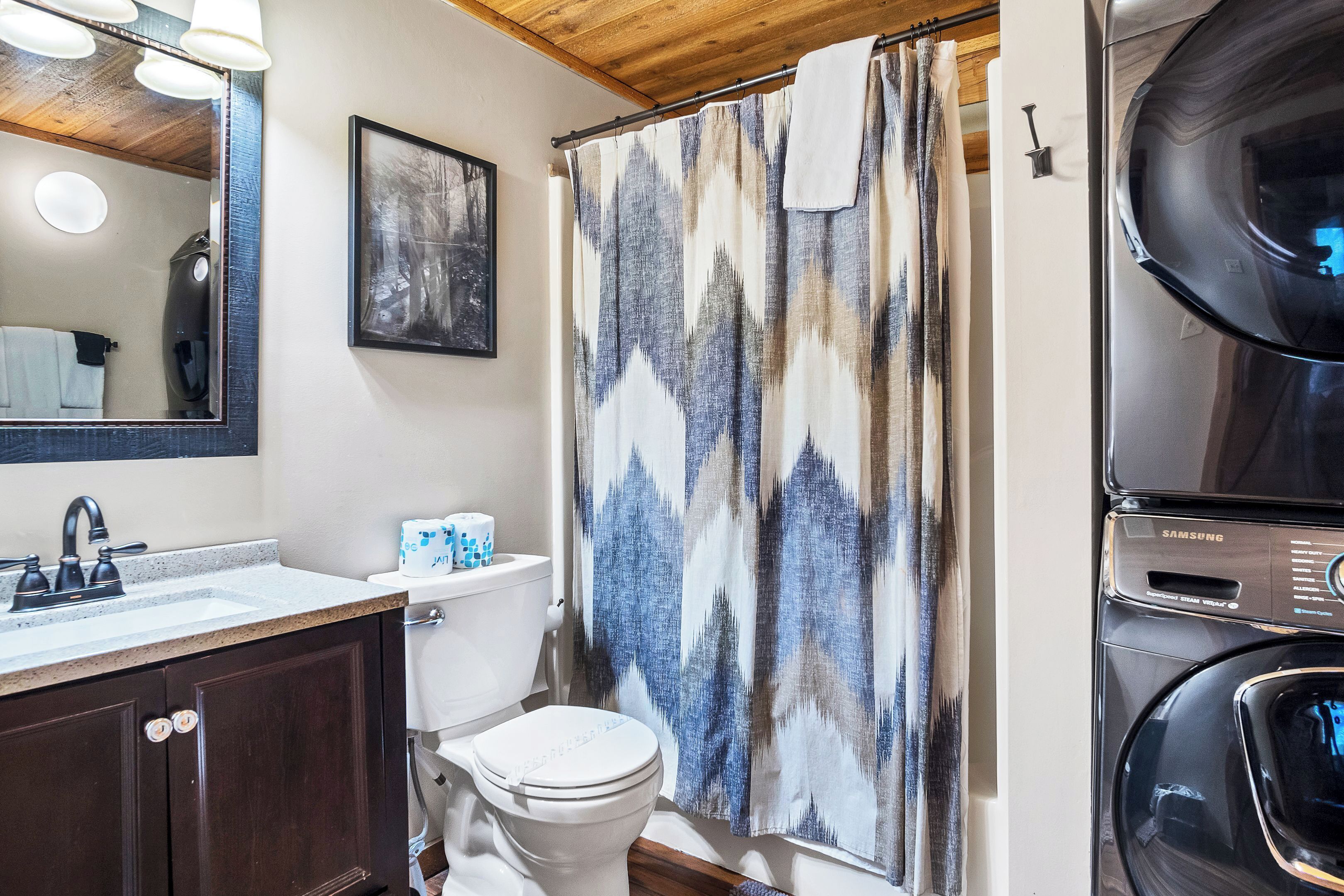 Une salle de bain équipée d’un lavabo, de toilettes et d’un lave-linge Samsung.