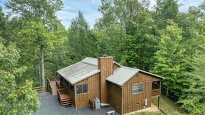 Une cabane en bois avec une véranda, une cheminée et une petite terrasse.
