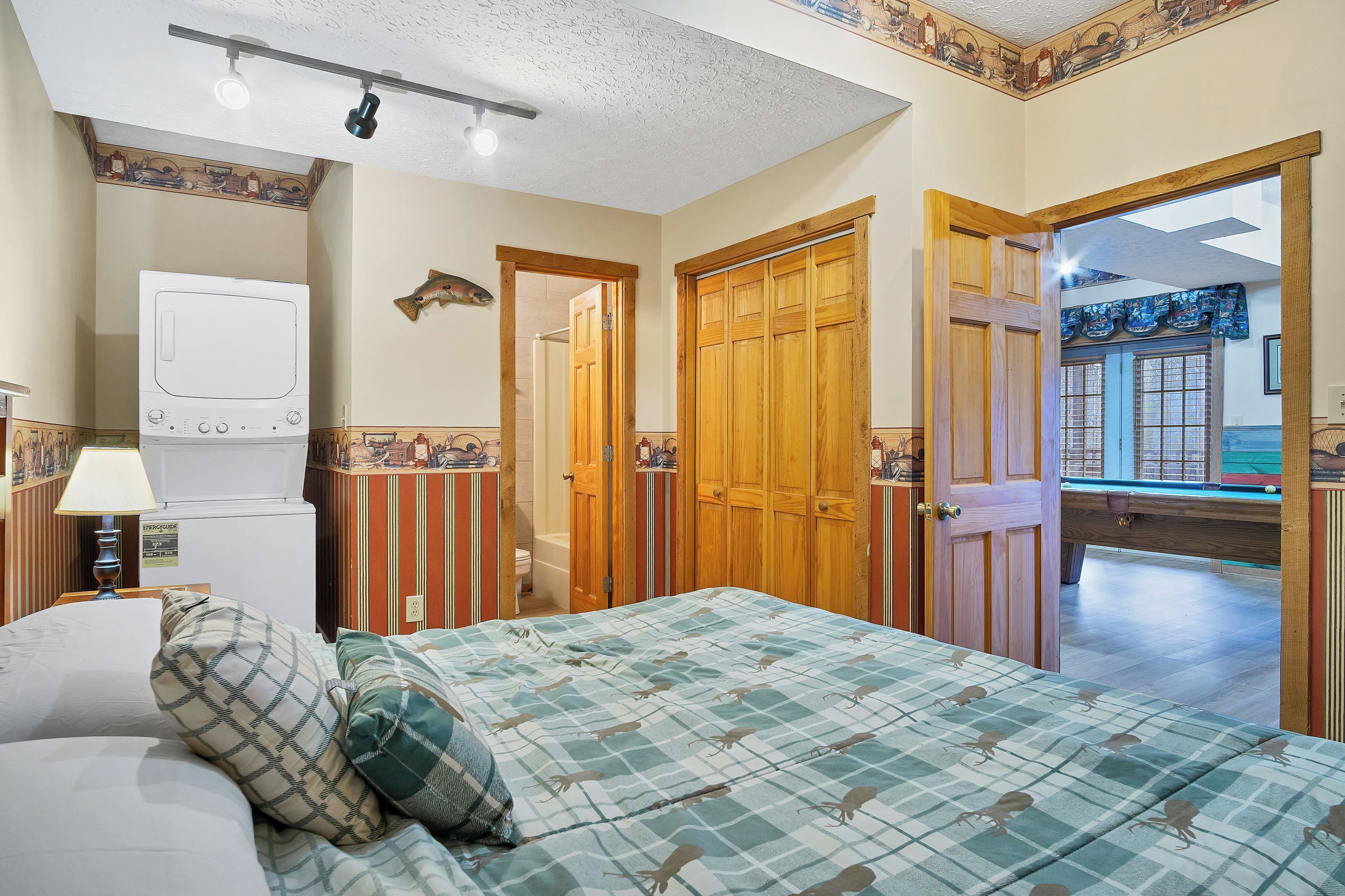 A bedroom with a bed, a dresser, a mirror, and a door leading to a bathroom.