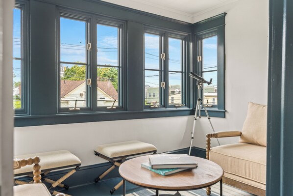 A room with a large bay window, a tripod, a round table, and a sofa.