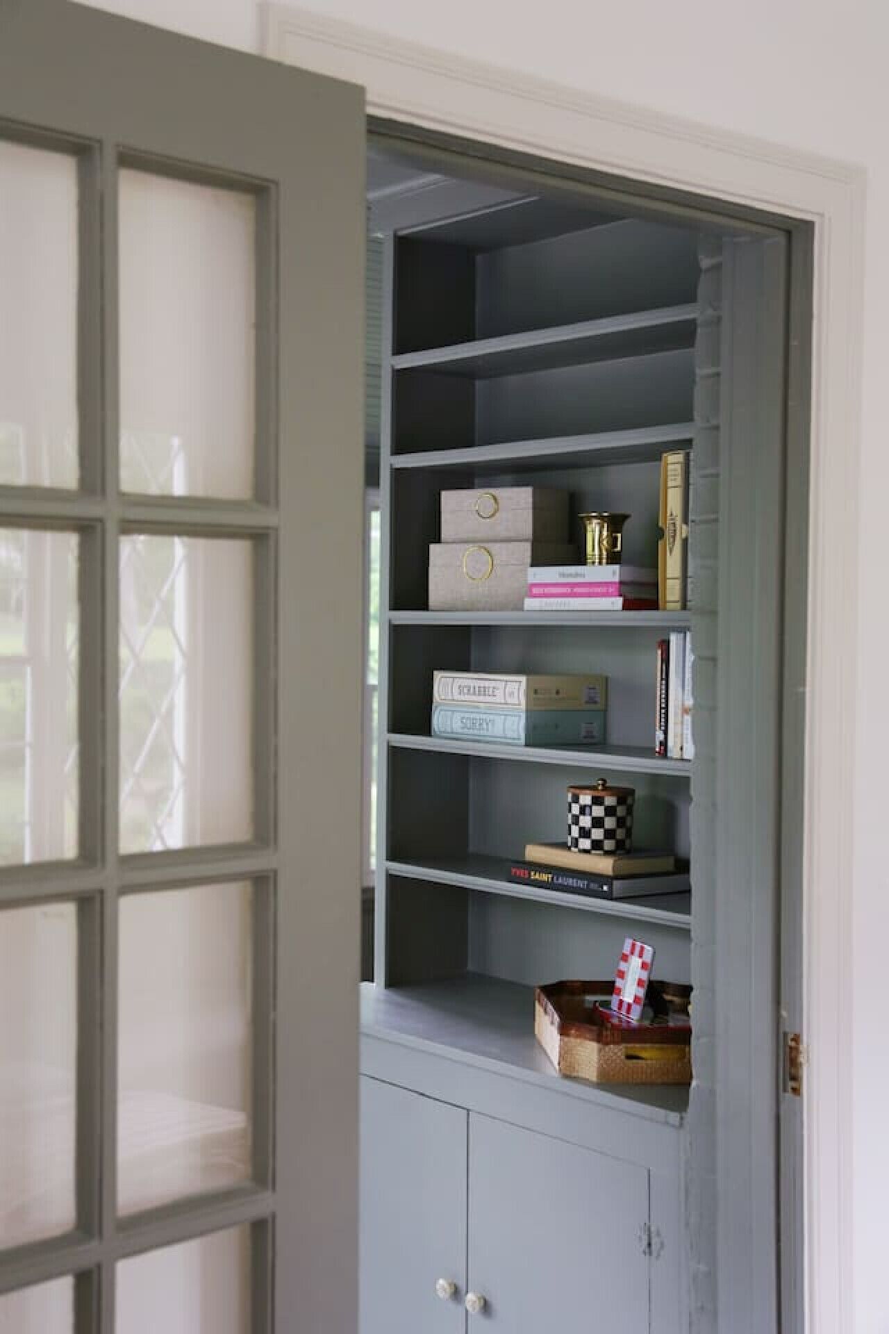 A grey built-in shelving unit with multiple shelves, some containing books and decorative items.