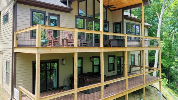 A multi-story house with a balcony on each floor, large windows, and a covered deck area.