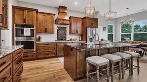 A modern kitchen with wooden cabinets, stainless steel appliances, and a large island with bar stools.