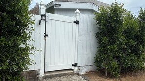 A white garage with a metal gate, surrounded by greenery.