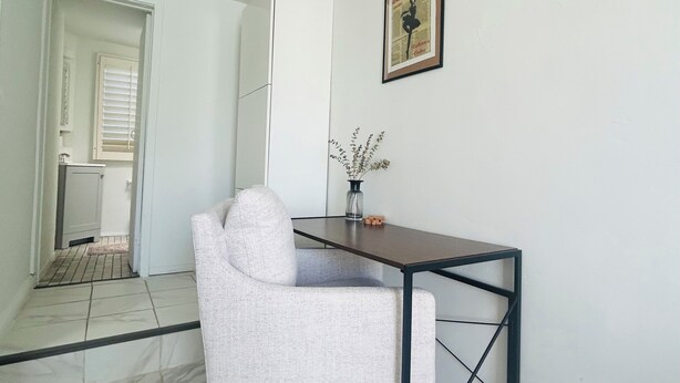 Une pièce moderne et minimaliste, avec un canapé blanc, une petite table et un tableau encadré au mur.